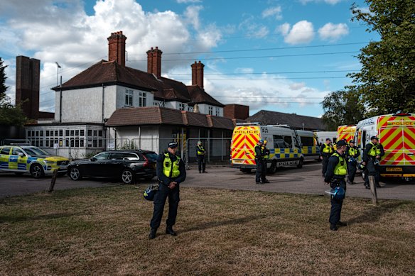 Politieagenten staan het Bell Hotel bewaken terwijl demonstranten zich buiten verzamelen.