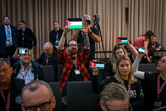Deelnemers aan de staatsconferentie van Labour op zaterdag verhogen digitale versies van de Palestijnse vlag op hun elektronische apparaten.