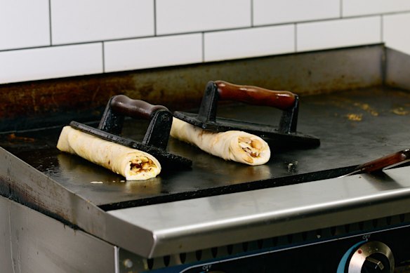 De shoarmawraps worden met een verzwaarde pers op de bakplaat afgewerkt.