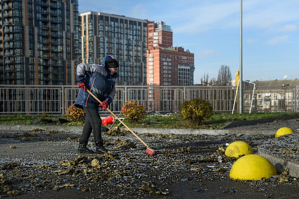 Een gemeentewerker veegt puin weg voor een woongebouw in Kiev dat dinsdag beschadigd werd tijdens Russische stakingen.