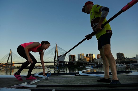 Roeiers van de Glebe Rowing Club bereiden zich voor om vóór de hitte van de dag het water van Blackwattle Bay op te gaan.